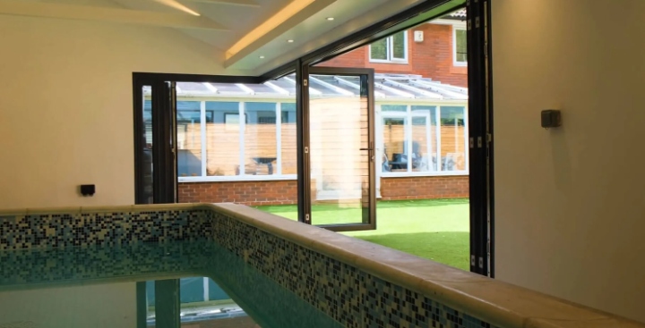 Stunning indoor pool area featuring modern slide and fold aluminium doors opening to a lush garden. Perfect for seamless indoor-outdoor living.