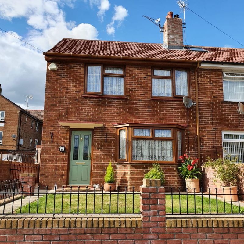 red brick house with chartwell green front door and timber effect windows